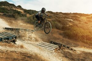 MTB bike rider jumping during downhill ride on his bicycle in mountains